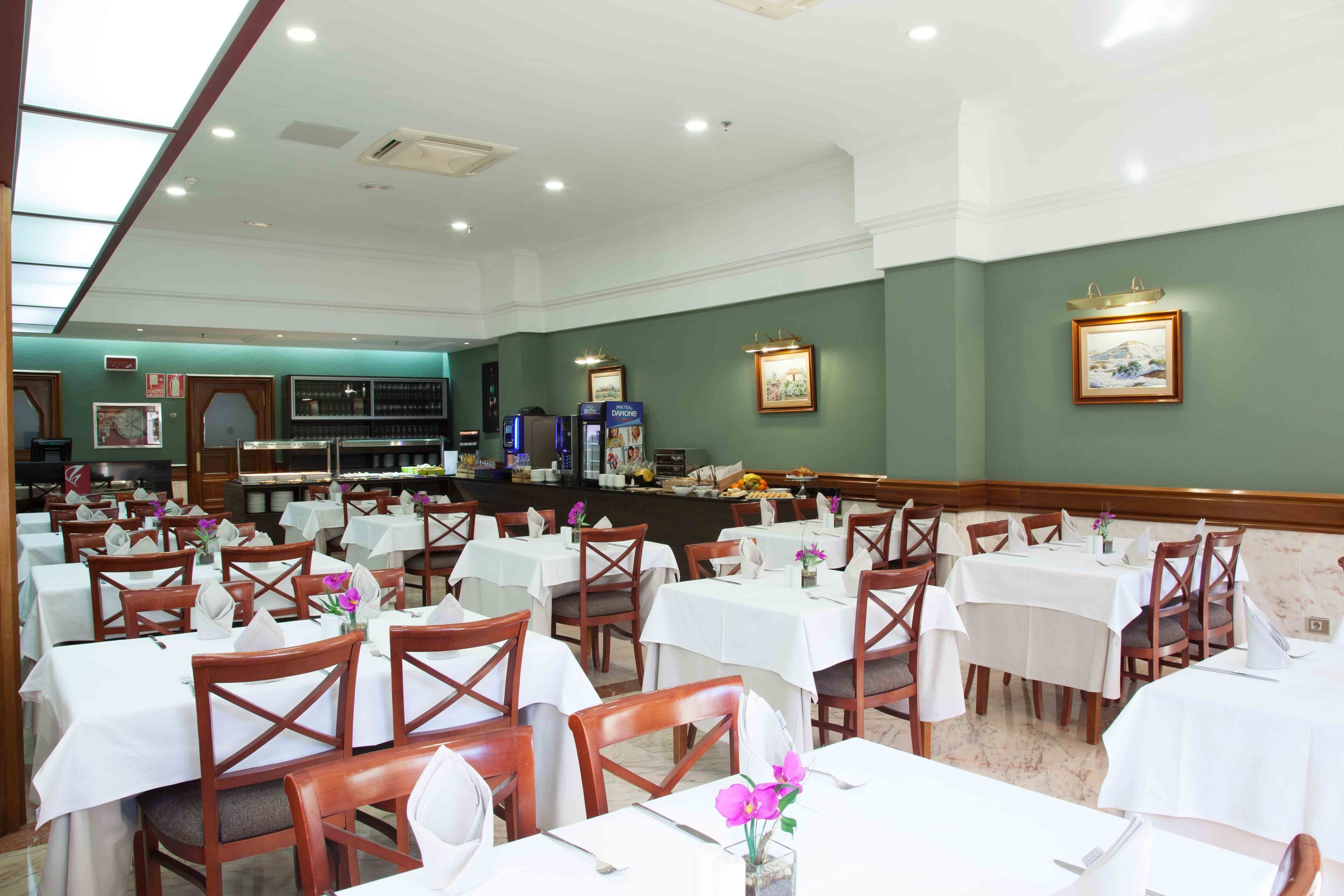 A dining area with multiple tables and chairs, a buffet counter, and framed pictures on the walls.