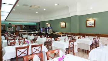 A dining area with multiple tables and chairs, a buffet counter, and framed pictures on the walls.