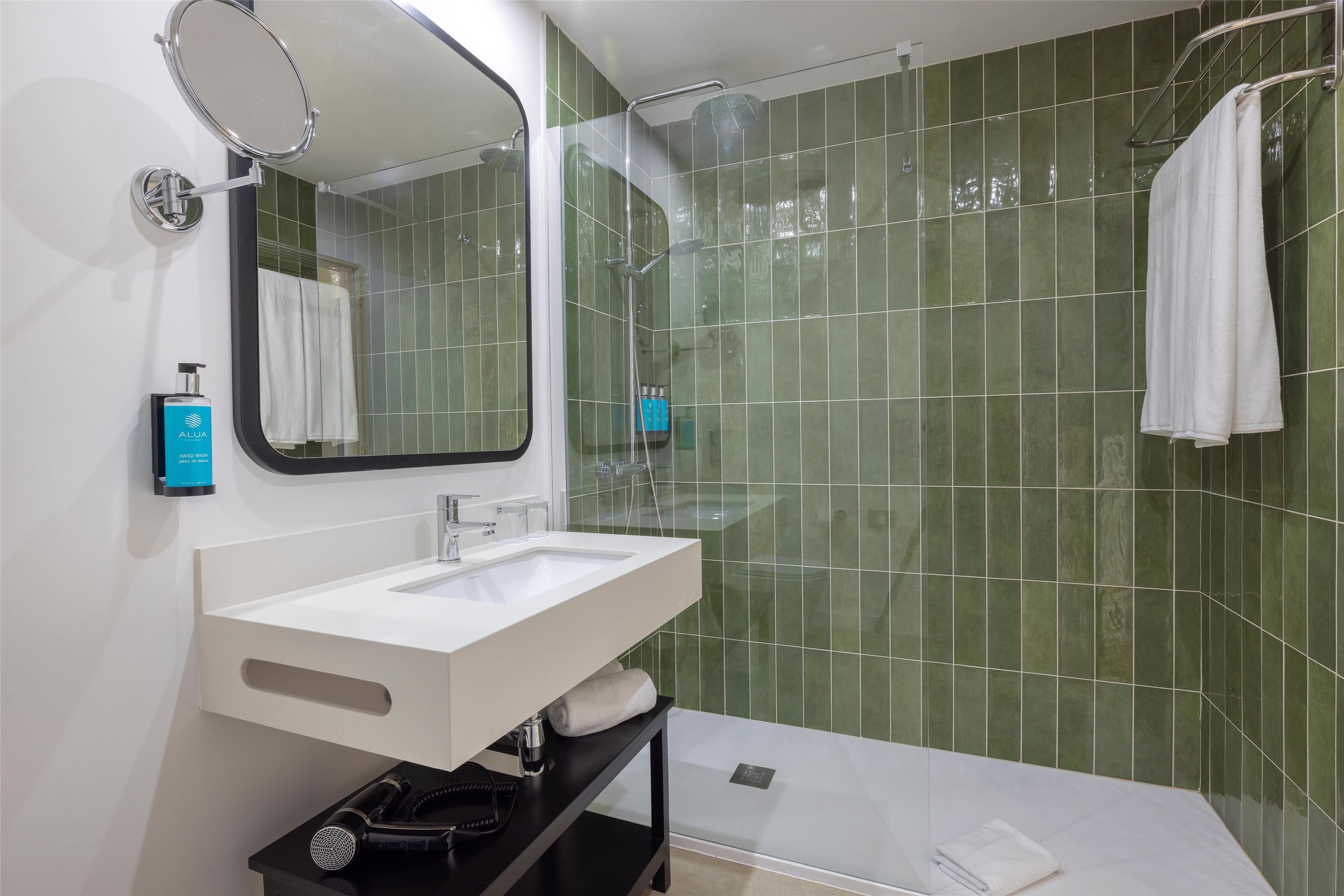 A modern bathroom with a white sink, mirror, and shower area.