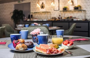 A breakfast setting with a plate of pastries, a bowl of fruit, and a glass of orange juice on a table. - Leonardo Hotel Barcelona Gran Via (Barcelona)