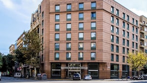Um hotel com vários andares e design moderno, com uma entrada imponente e varandas visíveis nos andares superiores.