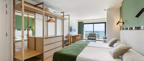 Habitación de hotel con cama, escritorio, silla, televisión y vista al mar.