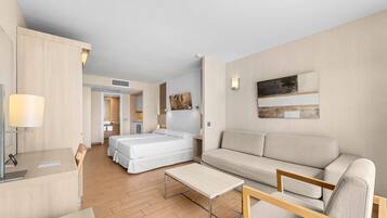 Una habitación de hotel moderna con suelo de madera, un sofá, una cama, un escritorio y una lámpara.