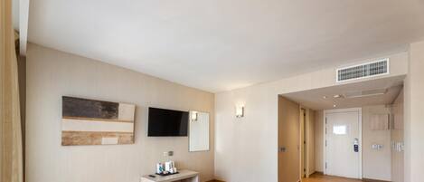 Una habitación de hotel con cama, escritorio, silla, televisor y armario.