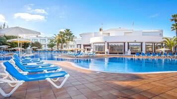 Een buitenzwembad, parasols bij het zwembad en ligstoelen