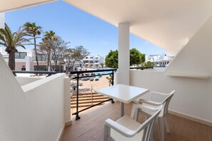 A balcony with a table and chairs, overlooking a pool and buildings. - Hotel THB Lanzarote Beach (Teguise)