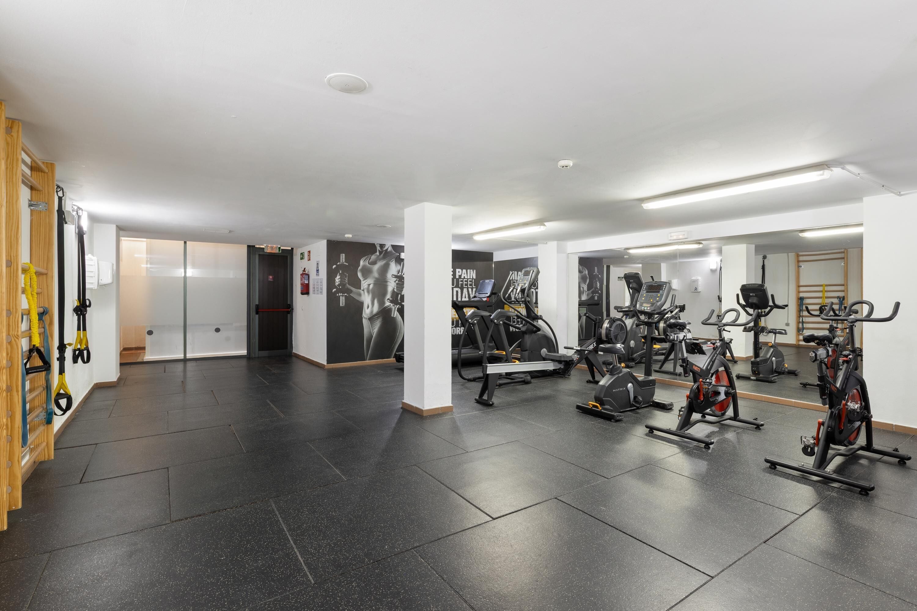 A gym with exercise equipment, a wooden rack, and a mirrored wall.