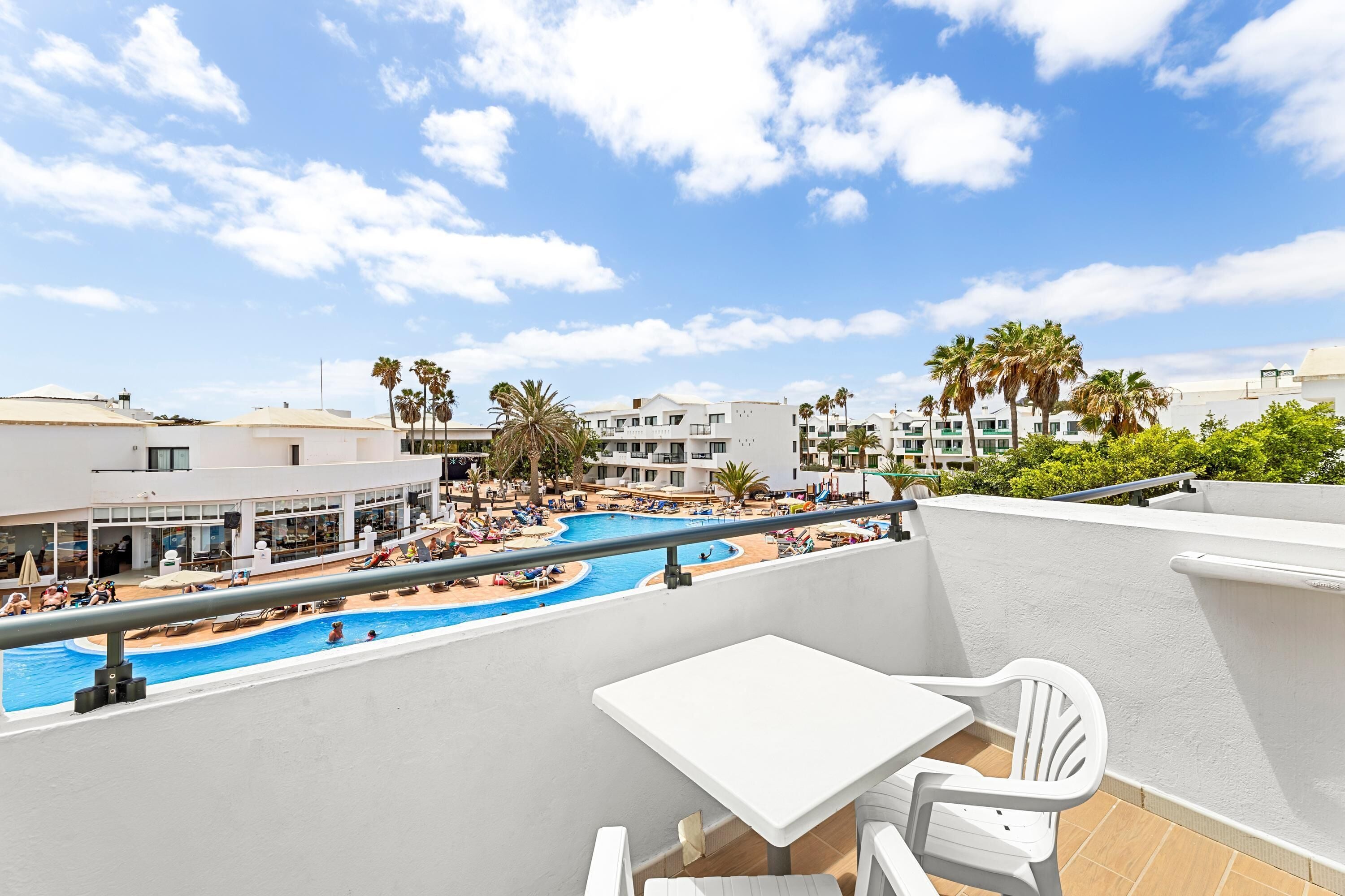 Un área de piscina en la azotea con vistas a los edificios y palmeras circundantes.