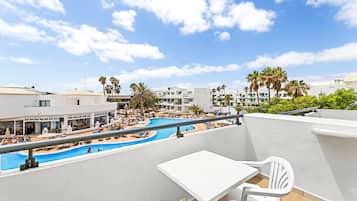 Un área de piscina en la azotea con vistas a los edificios y palmeras circundantes.