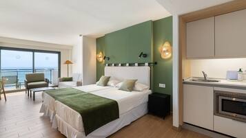 Un dormitorio con cama, mesita de noche, lámpara, vista al mar y kitchenette.