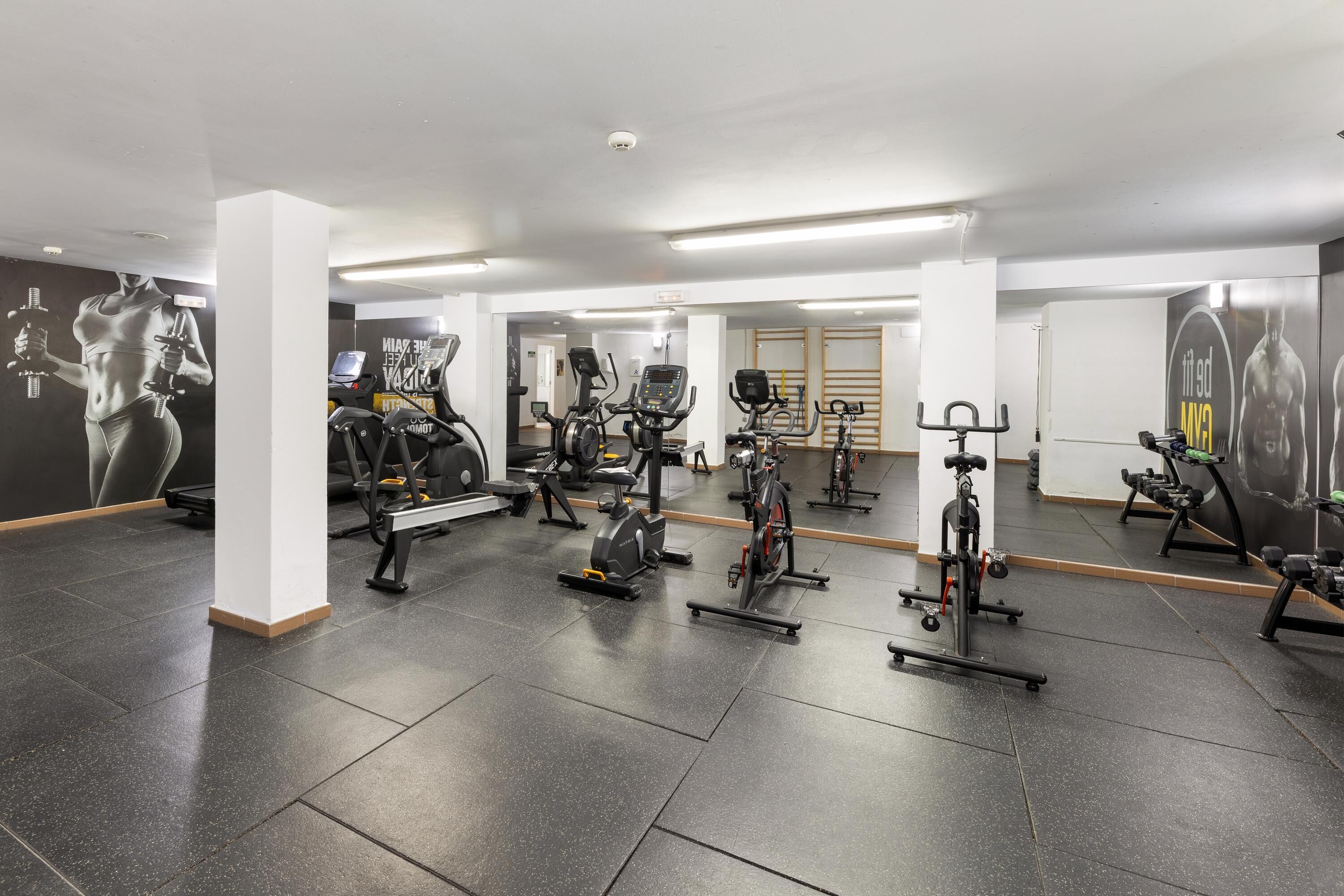 A gym with various exercise equipment, including treadmills, stationary bikes, and weight machines.