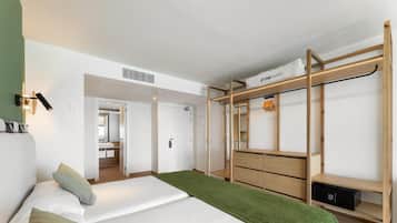 Een moderne hotelkamer met een bed, een houten garderobe, een spiegel en een zichtbare badkamer door een geopende deur.