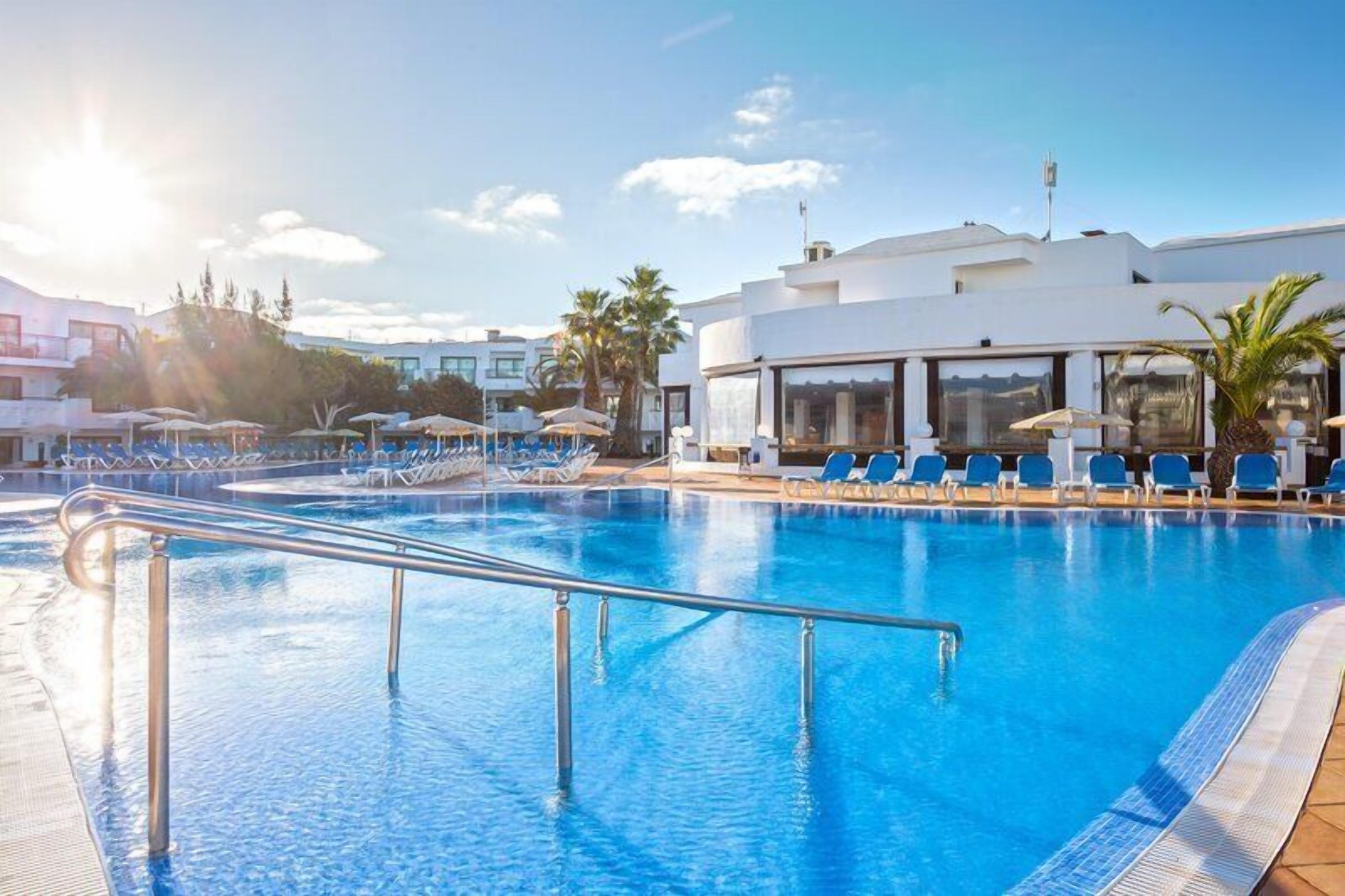 Una piscina al aire libre, sombrillas, tumbonas