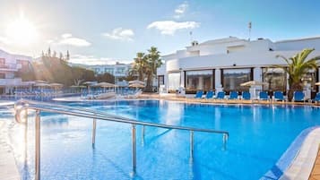 Una piscina al aire libre, sombrillas, tumbonas