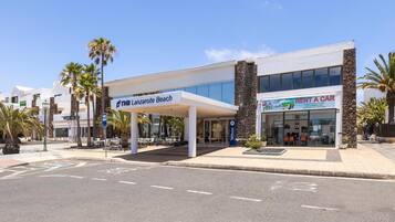 A modern building with a sign for 'Lanzarote Beach' and a 'Rent a Car' service.