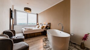 Un bagno moderno con una vasca freestanding, una grande finestra e un’area relax con sedute.