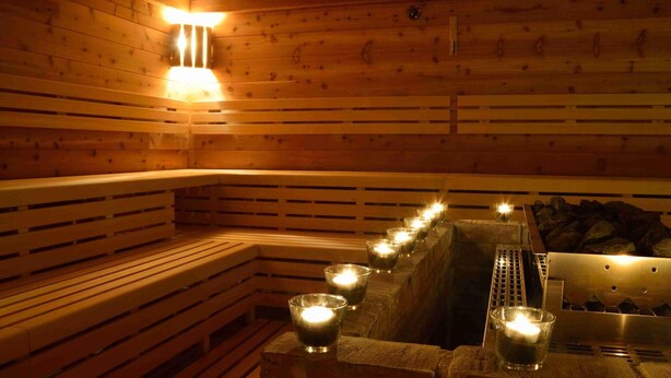 Una sauna in legno con panche e candele accese.