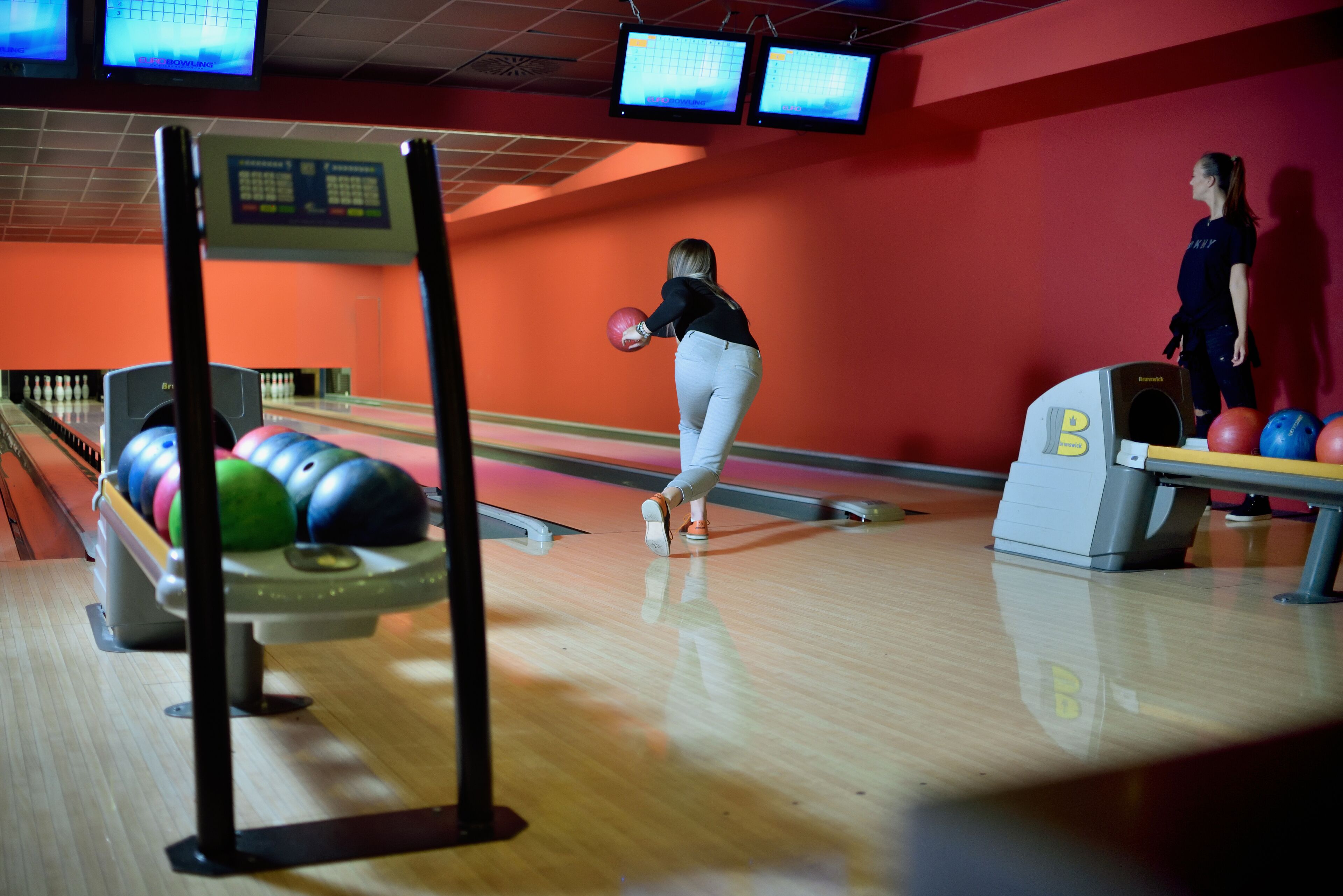 A bowling alley with lanes, bowling balls, and a scoreboard.