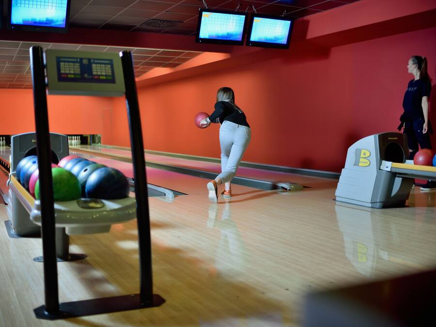 A bowling alley with lanes, bowling balls, and a scoreboard.