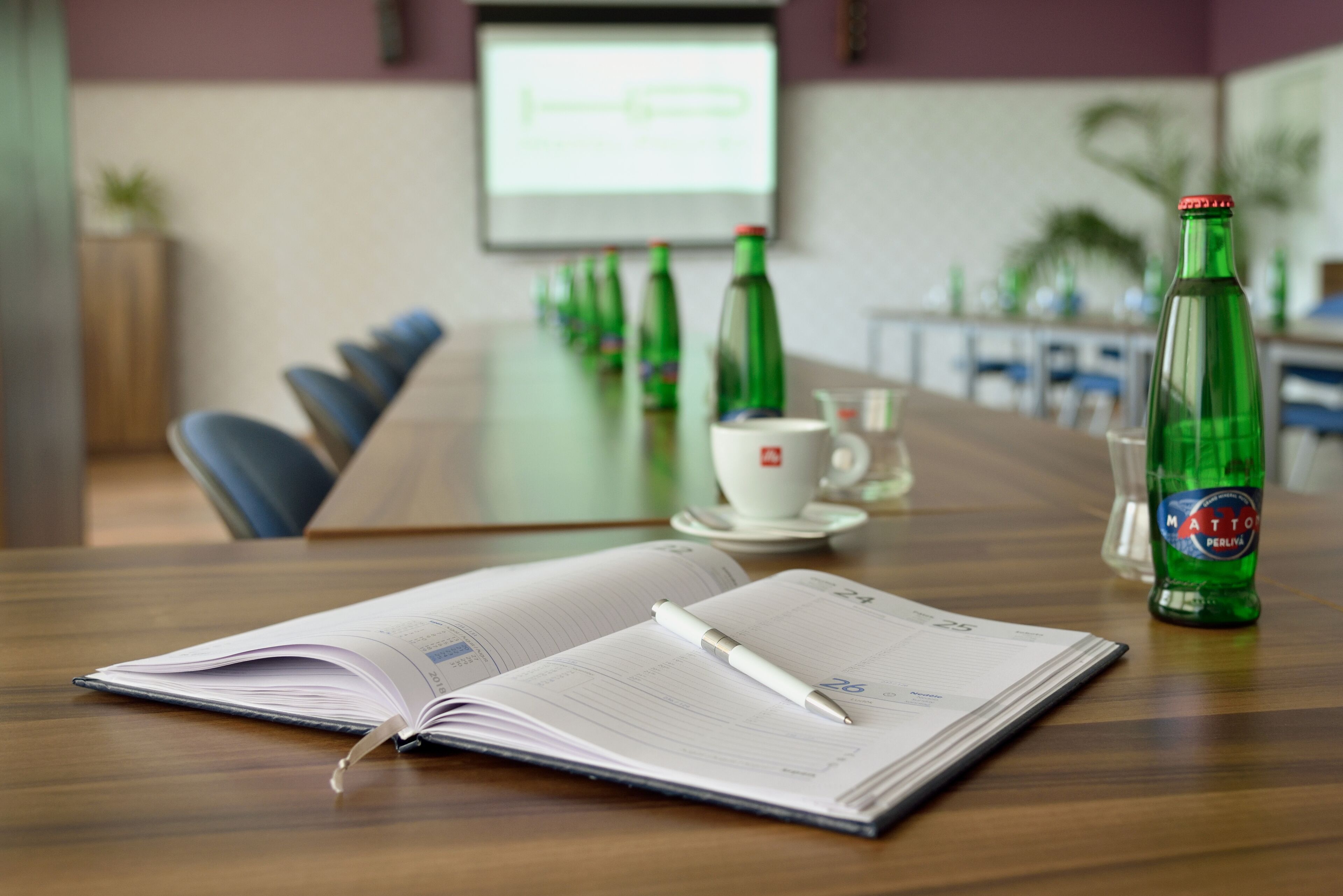 A conference room with a wooden table, a whiteboard, and several green bottles.