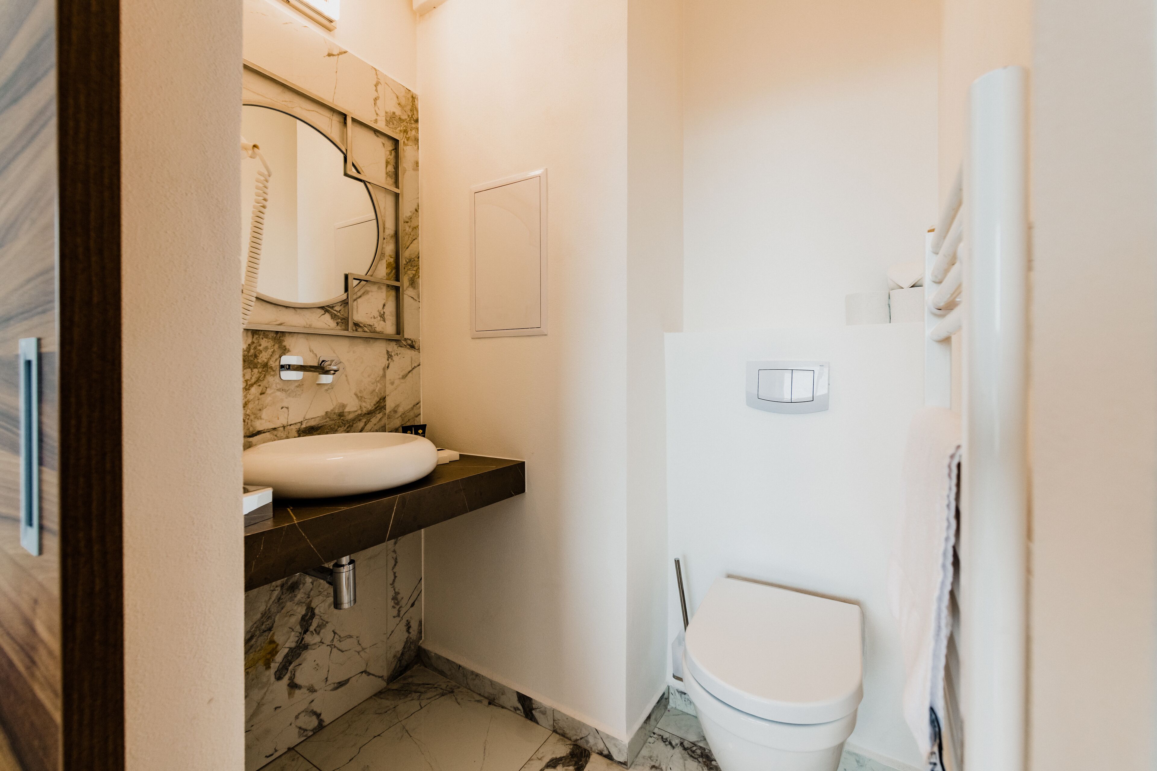 A bathroom with a marble sink, a toilet, and a shower.