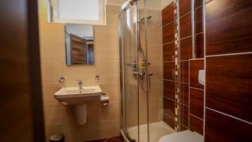 A modern bathroom with a glass-enclosed shower, a sink, and a toilet.