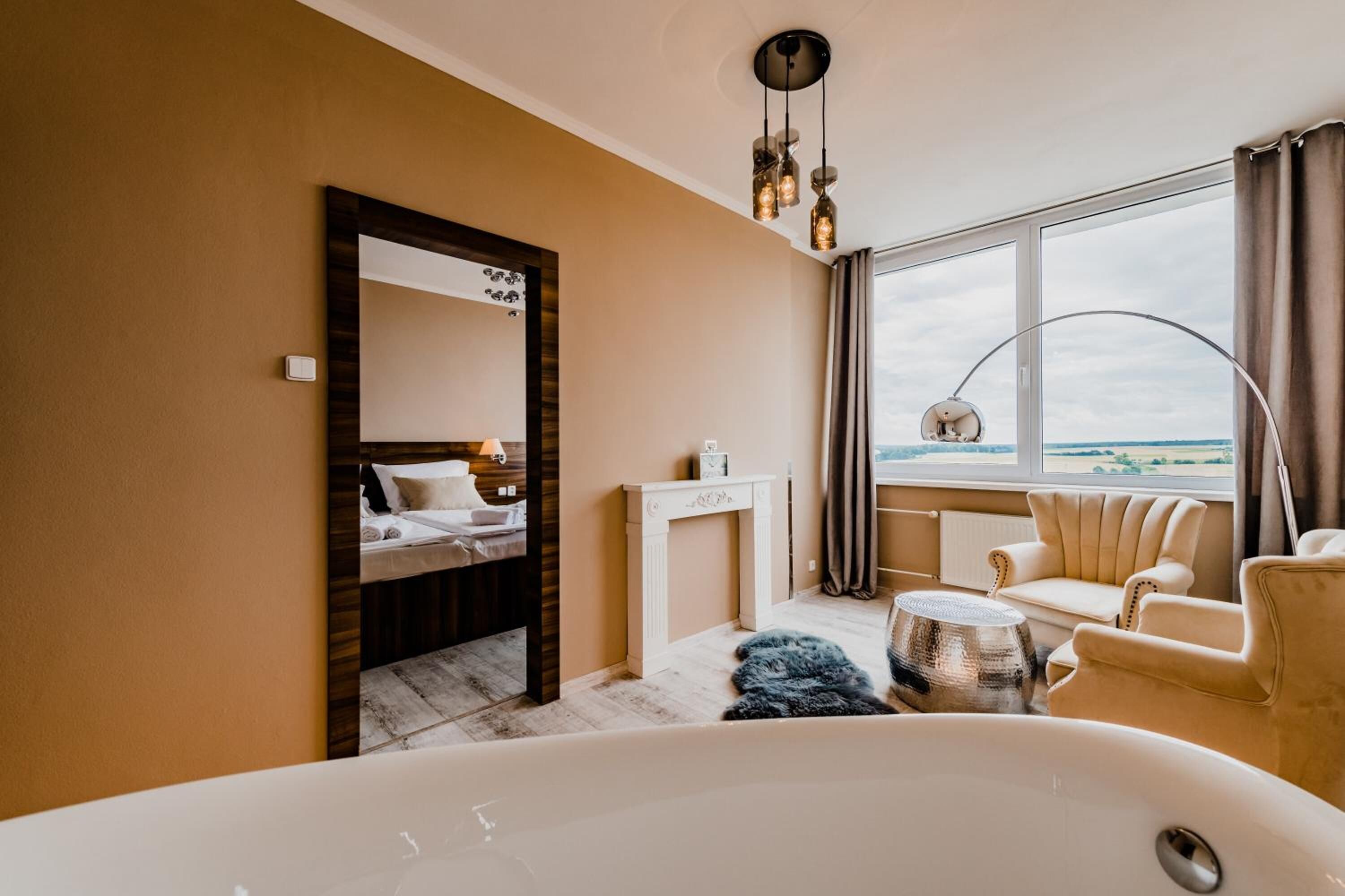 Moderni hotellihuone, jossa on suuri ikkuna, kylpyamme, sohva ja pieni pöytä.