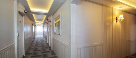 A hotel corridor with a checkered carpet, white walls, and a sign indicating the second floor.