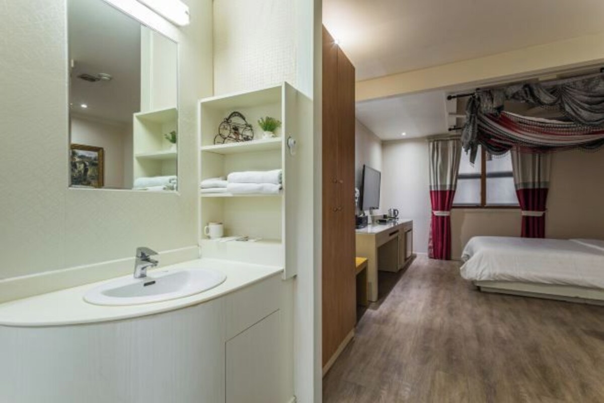A modern bathroom with a white sink, mirror, and shelves.