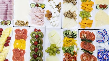Una varietà di cibi tra cui frutta, formaggi e salumi disposti su un tavolo.