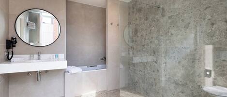 Un baño moderno con un espejo redondo, una bañera y una zona de ducha.