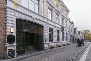 A historic building with a large entrance, a sign for a hotel, and a cobblestone street. - Dukes’ Academie – by Dukes’ Hotel Collection (Bruges)