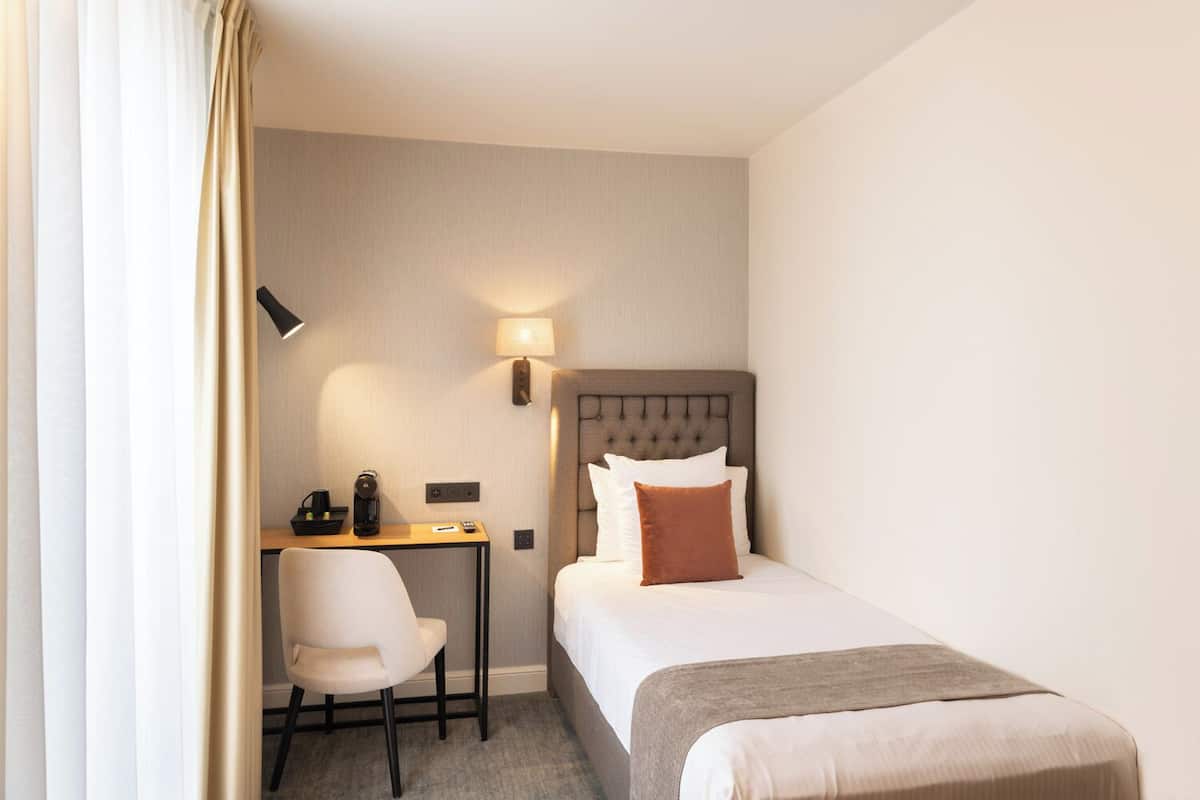 Ein Hotelzimmer mit Bett, Schreibtisch, Stuhl und Lampe.