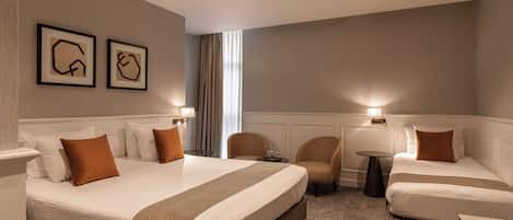 Una camera d'albergo con due letti, un angolo salotto con sedie, un tavolino e quadri appesi alla parete.
