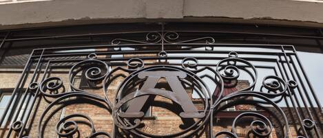 A wrought iron gate with a large 'A' emblem, part of a building's entrance.