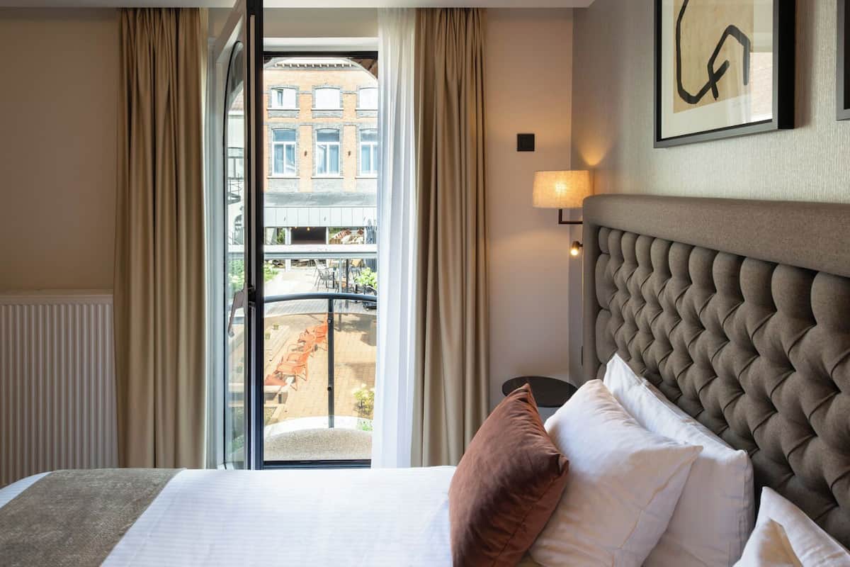 Ein Hotelzimmer mit Bett, Blick auf den Balkon und einer Wandleuchte.