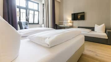 Una habitación de hotel con dos camas, un escritorio, una silla y un televisor en la pared.
