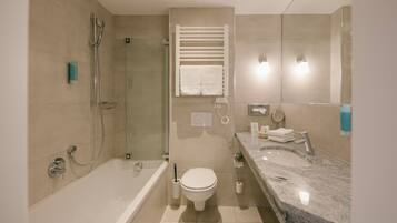 A modern bathroom with a bathtub, toilet, and a shower area.