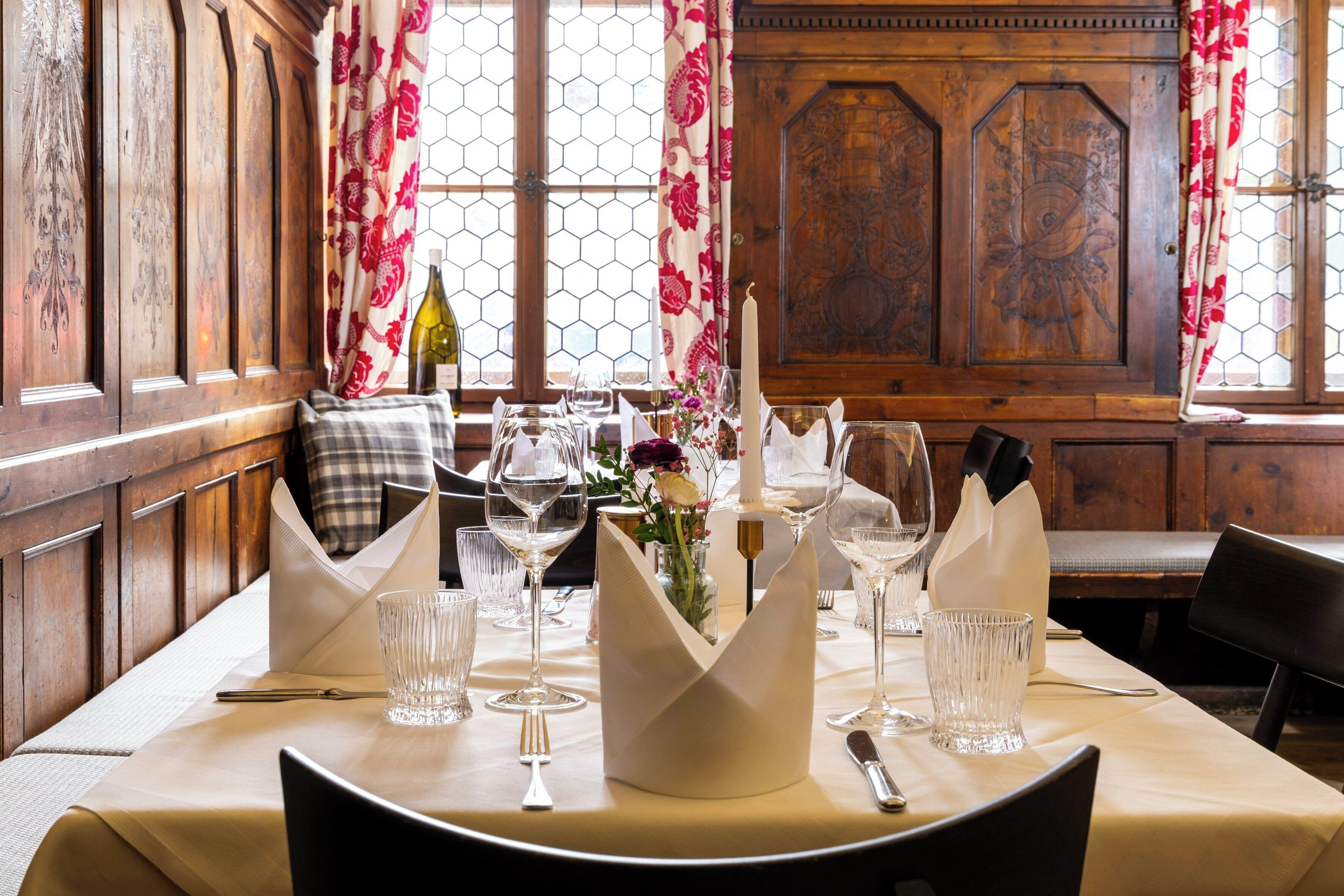 A dining table set with wine glasses, a candle, and a vase of flowers.