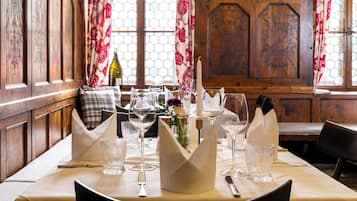 A dining table set with wine glasses, a candle, and a vase of flowers.