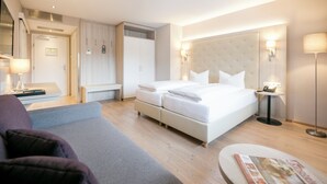 Una habitación de hotel con cama, mesitas de noche, escritorio, silla, armario y lámpara.