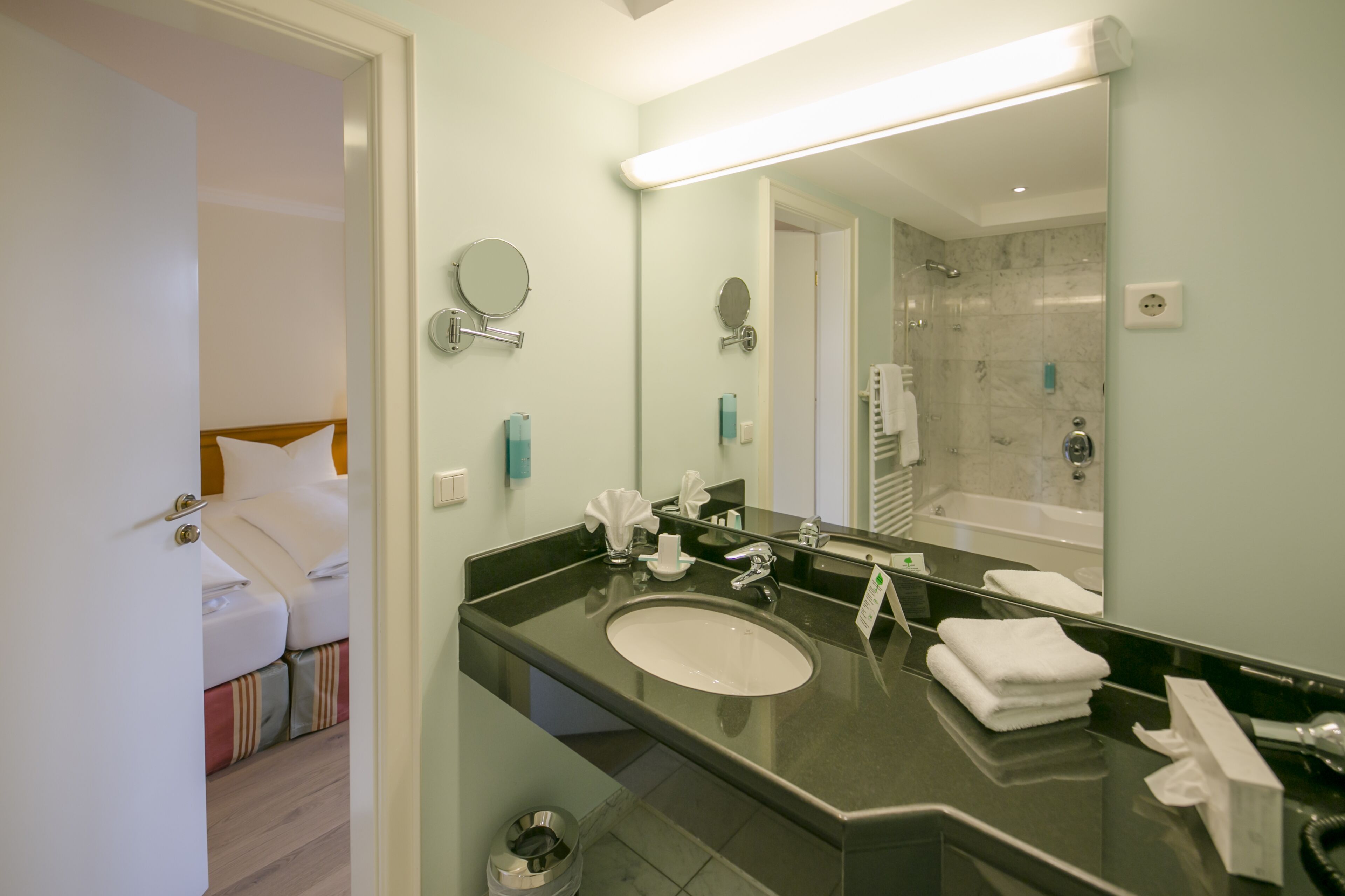 A modern bathroom with a large mirror, a sink, and a shower area.