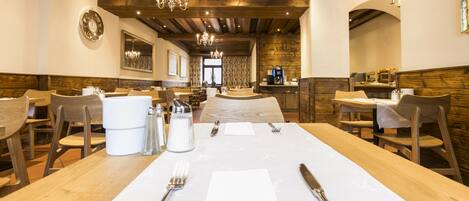 A restaurant with wooden tables and chairs, a chandelier, and a clock on the wall.
