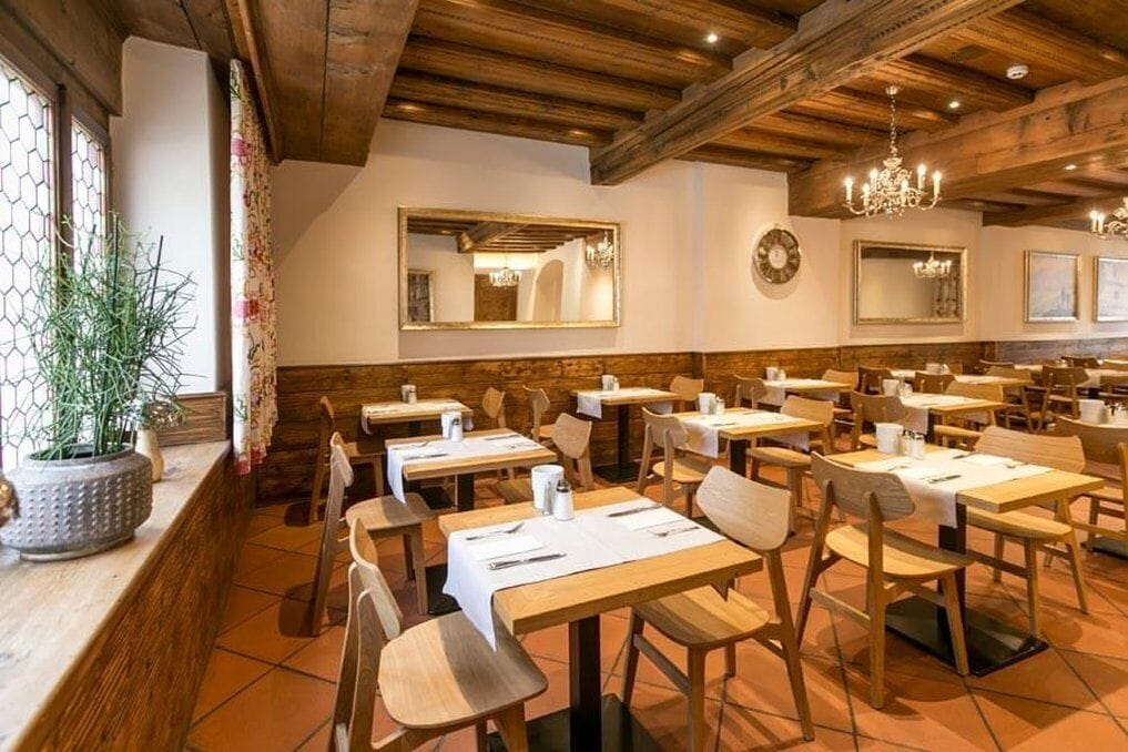 Un ristorante con tavoli e sedie in legno, un grande specchio e un lampadario.