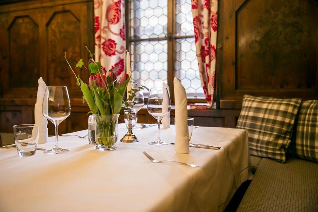A table set for dining with a vase of flowers, wine glasses, and a candle.