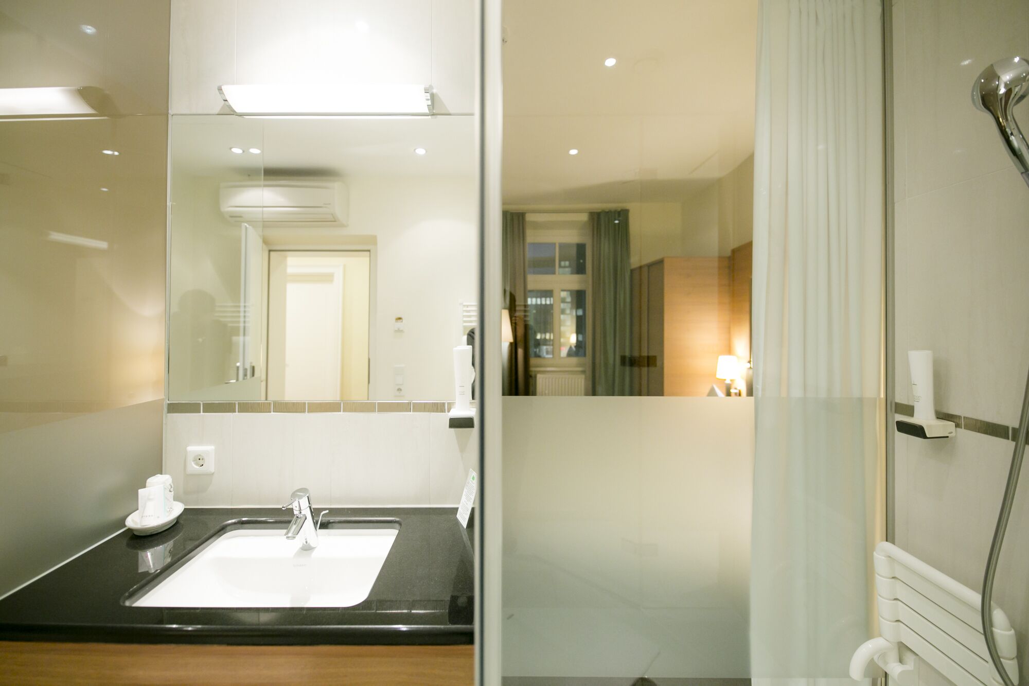 Un baño moderno con un espejo grande, un lavabo y una zona de ducha.