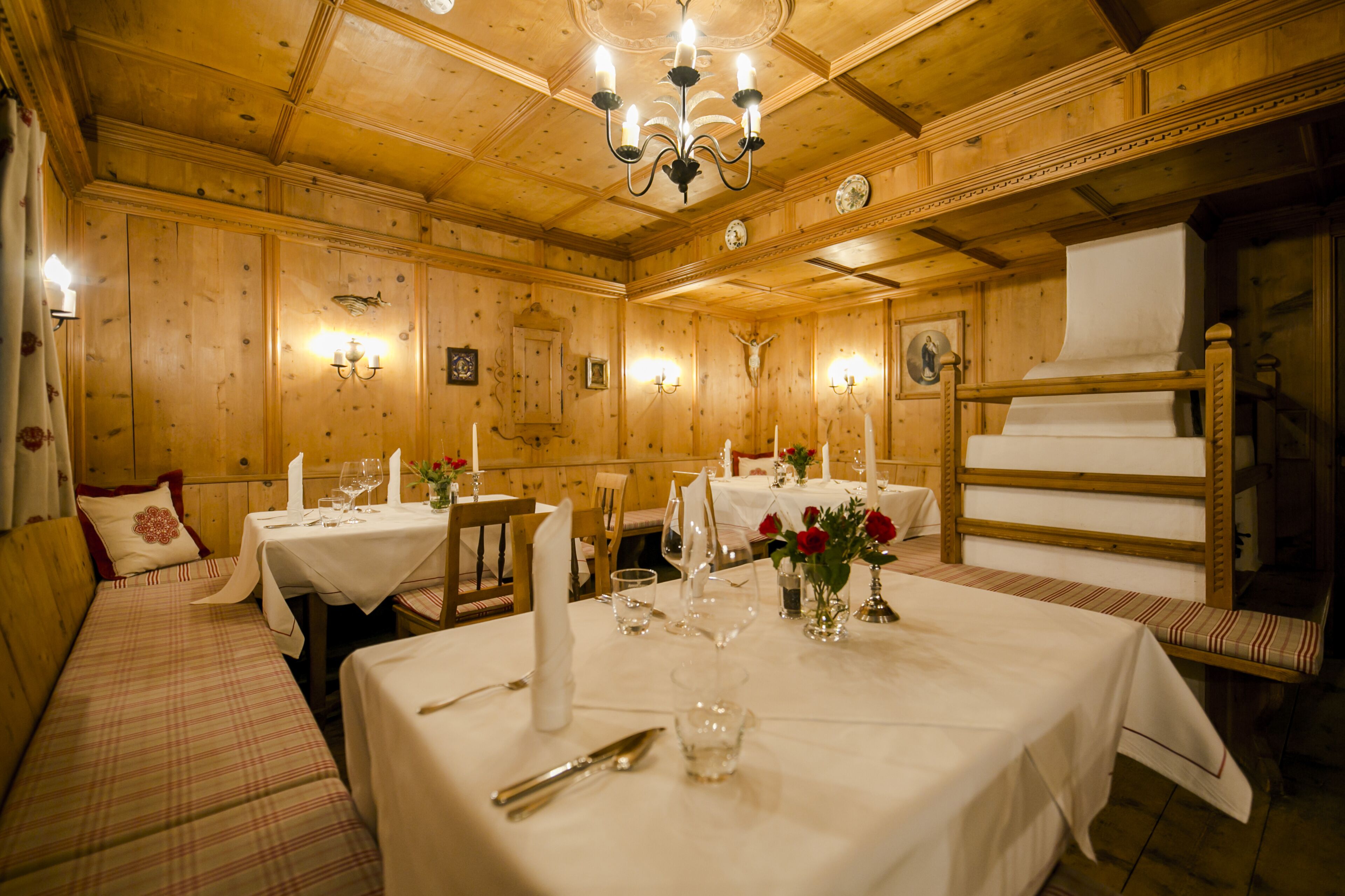 A wooden interior with tables set for dining, benches, and a chandelier.