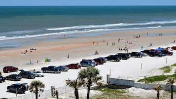 A beach with a parking lot and a few people walking.