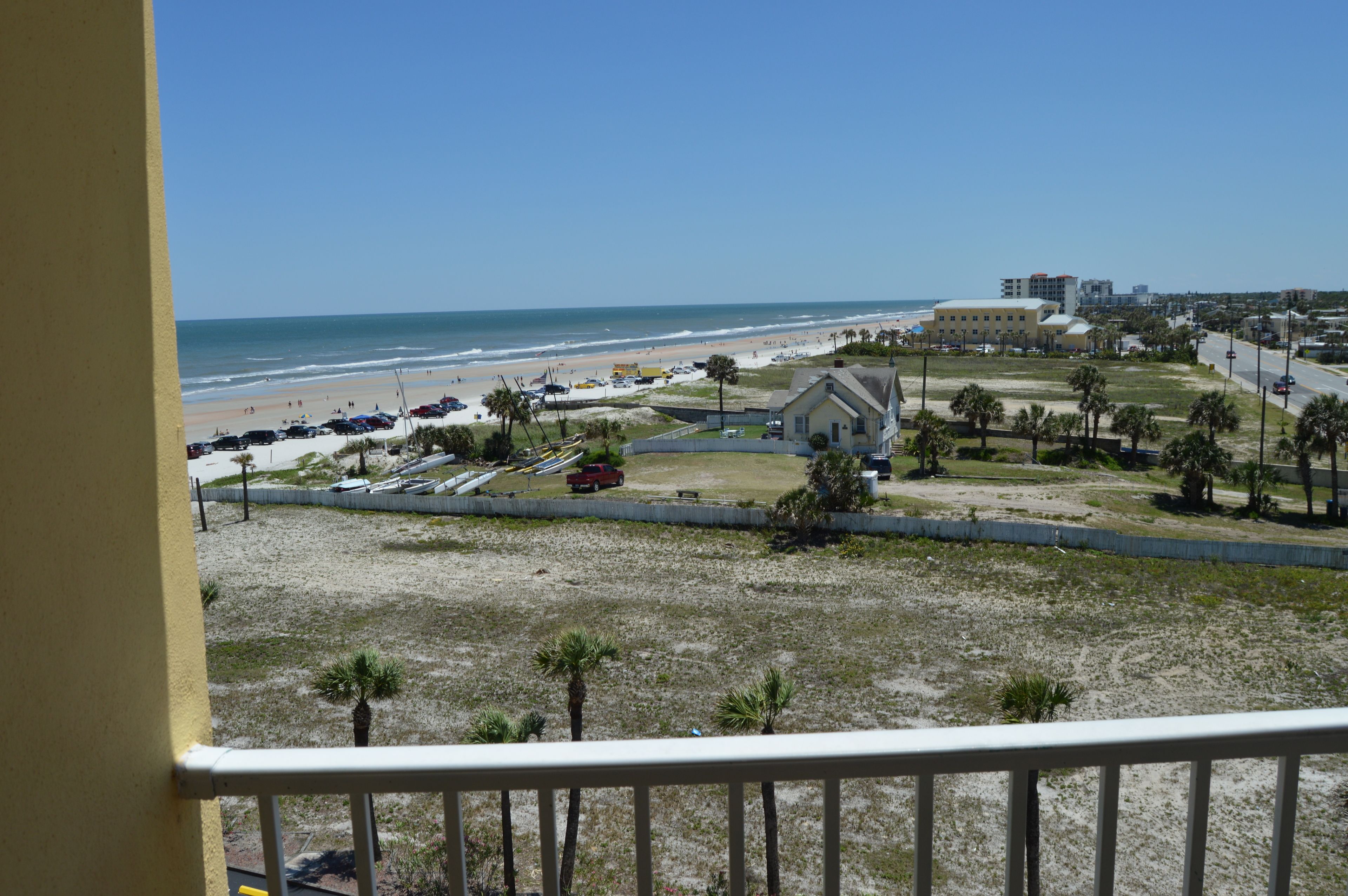 A beach view with a building, palm trees, and a clear sky.