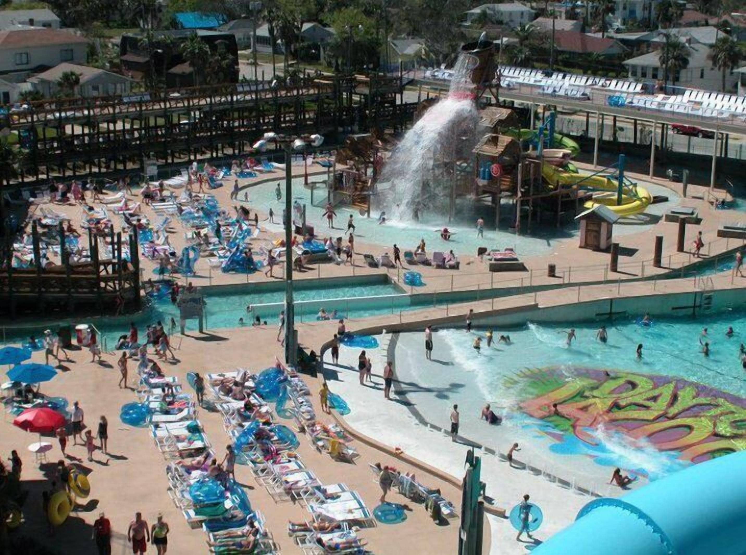 Ein Wasserpark mit mehreren Pools, Rutschen und einem großen Wandgemälde.